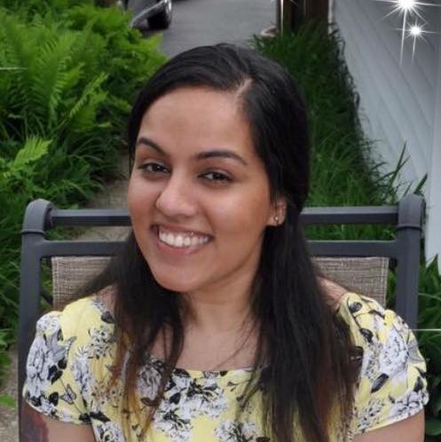 Picture of smiling me, wearing a yellow floral dress, sitting in the yard