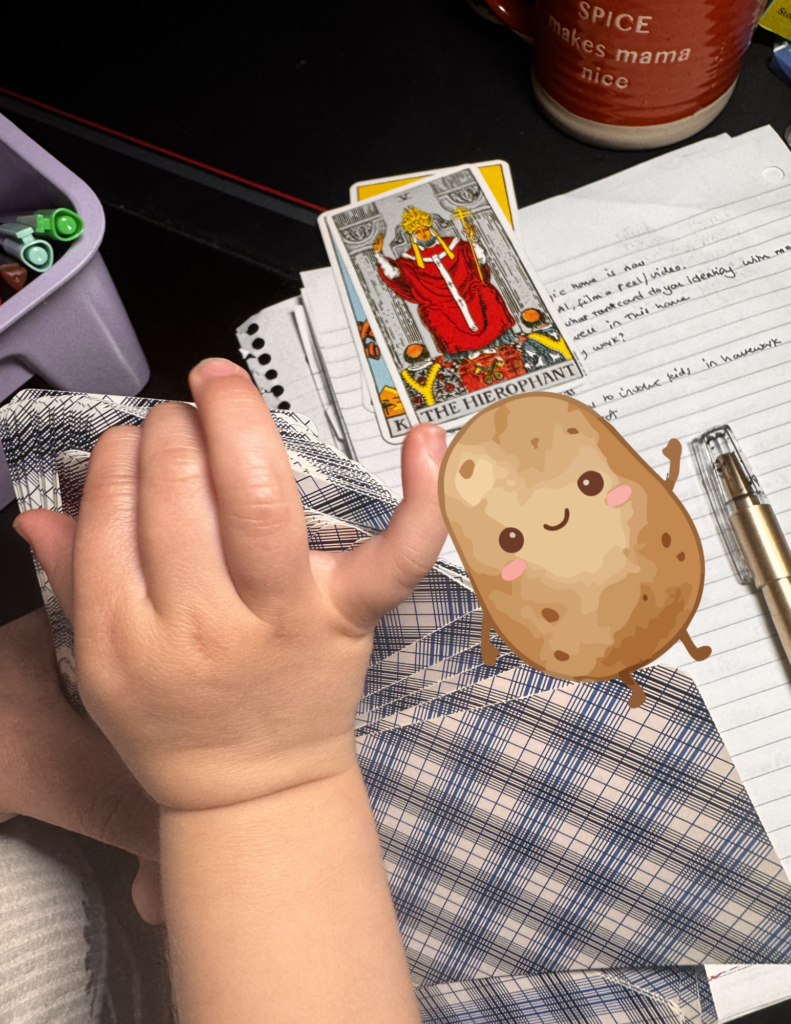 Toddler hands playing with tarot cards, and The Hierophant seen in the background