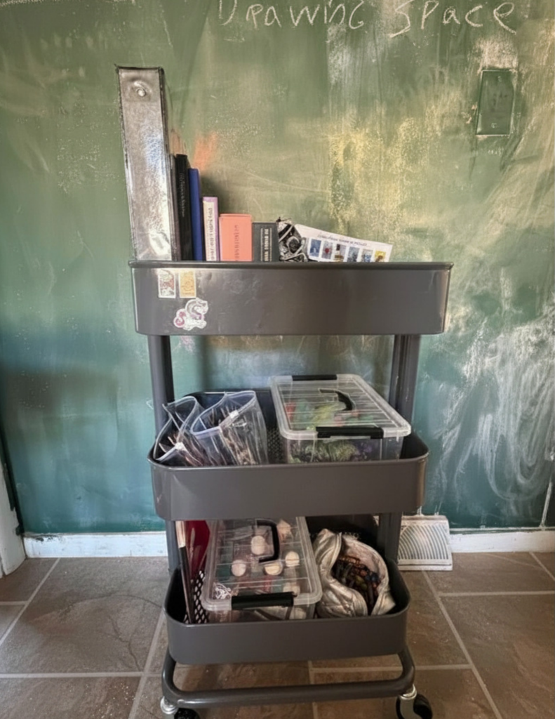 Rolling cart with various items on it, with a dusty chalkboard behind it 
